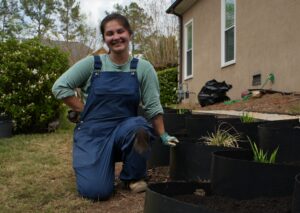 A beautiful woman poses next to the Dirtlocker terracing she recently installed, full of native plants